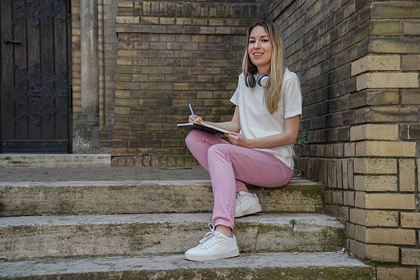 istock Young female student studying outdoors with smartphone, tablet, and notebook – modern education and student lifestyle 2222472821