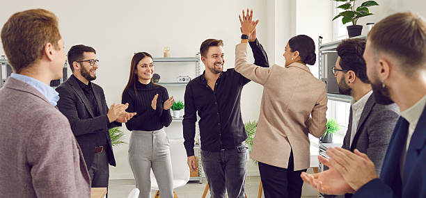 istock Two young men doing high five while their cheerful coworkers applauding them 2222473194