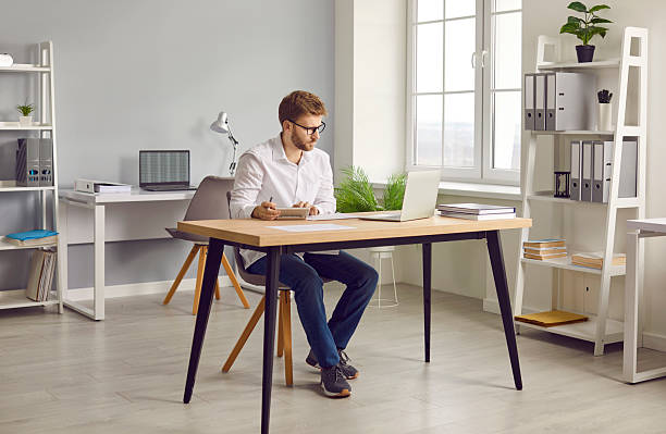 istock Young focused serious business man working on laptop at office making calculations. 2222473638