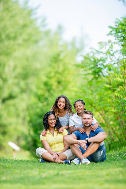 istock Happy Mixed Race Family Posing Outdoors in Sunlit Green Environment 2222474315
