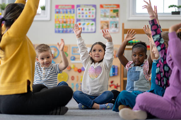 istock Children Raising Hands in Group Activity at Colorful Classroom Setting 2222475611