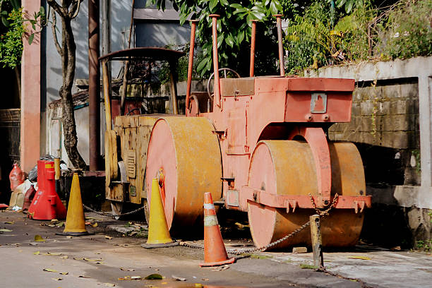 The roller itself is predominantly orange or rust-colored, with some yellow accents, and shows signs of age and use. It has two large, heavy rollers at the front and back