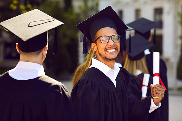 istock Excited college graduate man in black mortar board cap holding diploma 2222476070