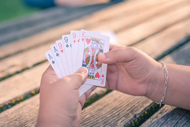 istock Woman's hand holding playing cards at a table 2222477027