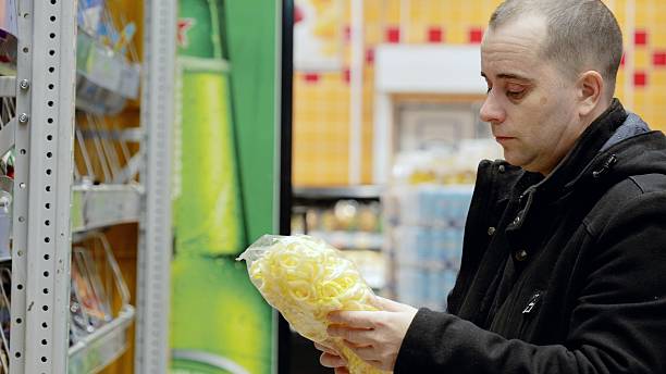 Male shopper reading snack bag label, comparing nutritional information and making mindful grocery selections for personal wellness and dietary awareness