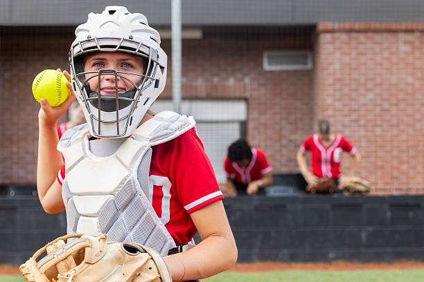 Catcher throws ball back to pitcher during softball game at rural high school