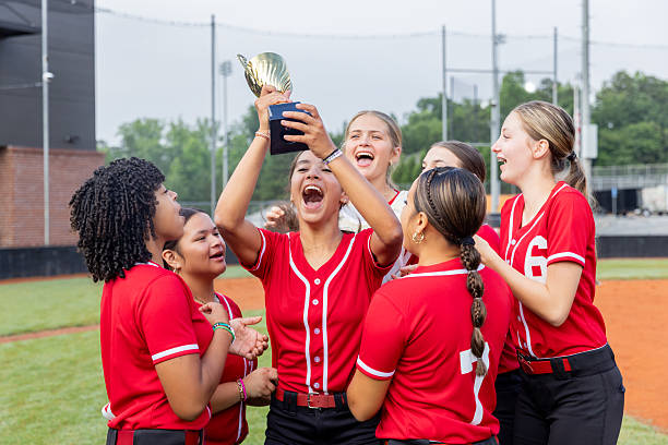 istock Softball team celebrates victory while lifting trophy on field at high school stadium 2222484870