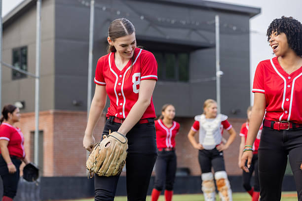 istock Softball player laughs with teammate while playing game at high school 2222485591