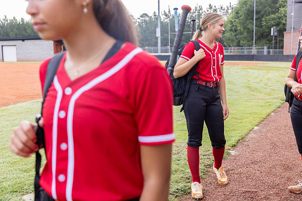 istock High school athletes talk while walking with equipment bags on softball field 2222486326