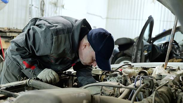 istock Skilled mechanic checking car engine, wearing protective gear in well lit automotive workshop, focusing on detailed technical maintenance and repair work 2222487868