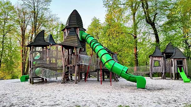 This video highlights a lively playground with a large green slide at its center, where children play and interact with equipment, while a charming castle adds a whimsical touch