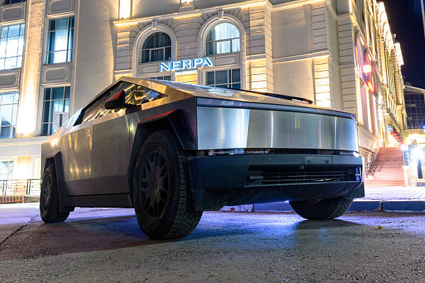 Ulyanovsk, Russia - October 20, 2024: A futuristic Tesla Cybertruck captured at night, with bright lights reflecting off its metallic surface, creating a striking contrast with the modern city.