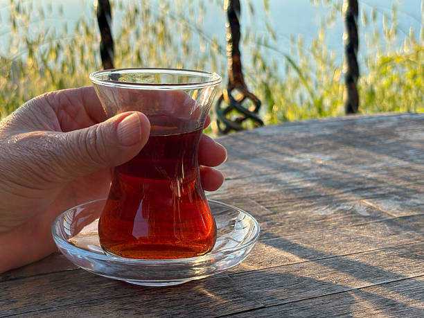 Turkish tea. Close-up of a female hand holding Turkish tea in an outdoor cafe or restaurant with sea background. Drinking Turkish tea