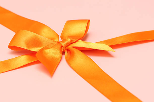 Orange wedding gift box mockup for branding or text. Arranged with pink floral wrist corsages and gold ribbons. Elegant celebration favor and bridal accessory concept.