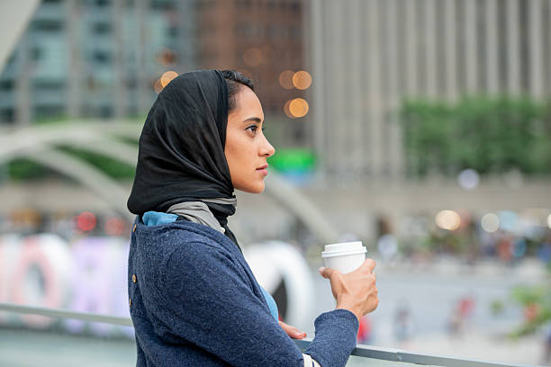 Young Woman Enjoying Coffee Outdoors in a Bustling Urban Setting