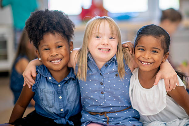 istock Three Diverse Children Smiling and Embracing in a Cheerful Classroom Setting 2222514074