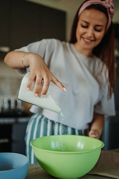 Young caucasian woman making bread dough in her kitchen