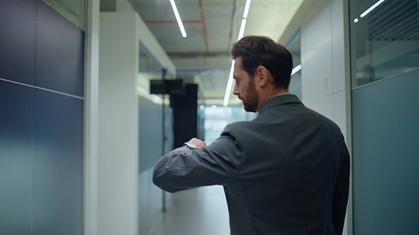 istock Formal suit director going empty vestibule back view. Man looking watches alone 2222516234