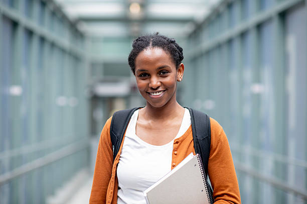 Confident Female Student Smiling While Holding Notebook in Modern Educational Setting stock photo