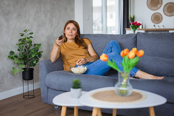 istock Woman relaxing on sofa watching tv and eating popcorn 2222526842
