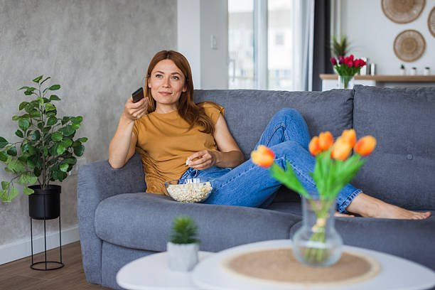 istock Woman relaxing on sofa watching tv and eating popcorn 2222526846