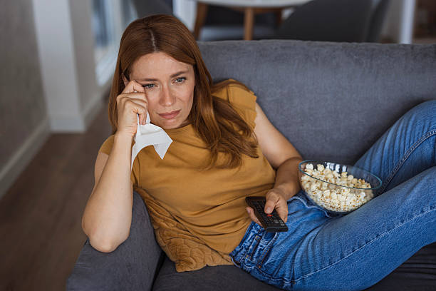 istock Sad woman is crying while watching tv and eating popcorn on the sofa 2222526906