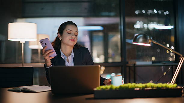 istock Office woman using smartphone at night feeling tired closeup. Lady drinking tea 2222530590
