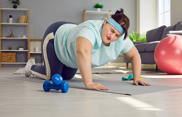 istock Funny exhausted overweight woman doing difficult push ups on exercise mat at home 2222530804