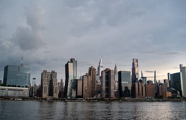 Dramatic clouds over city. Skyscrapers line waterfront under moody sky.