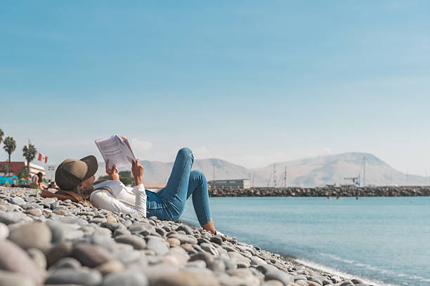 Tourist reading on a pebble beach enjoying vacation in chile