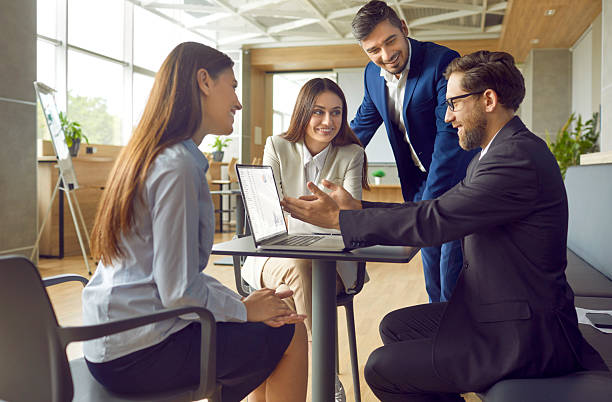 istock Smiling Business Team Collaborates in Office Using Laptop 2222535910