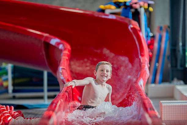 Child having fun on a bright red water slide while enjoying a day at the indoor swimming pool.
