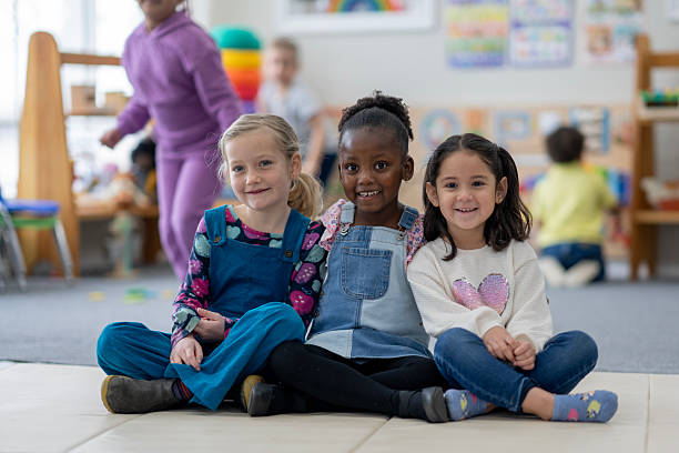 istock Three Happy Children Sitting Together in a Colorful Classroom Setting 2222541674