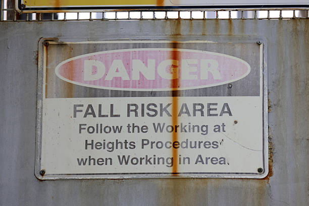 Weathered Danger Fall Risk Area sign attached to a concrete wall