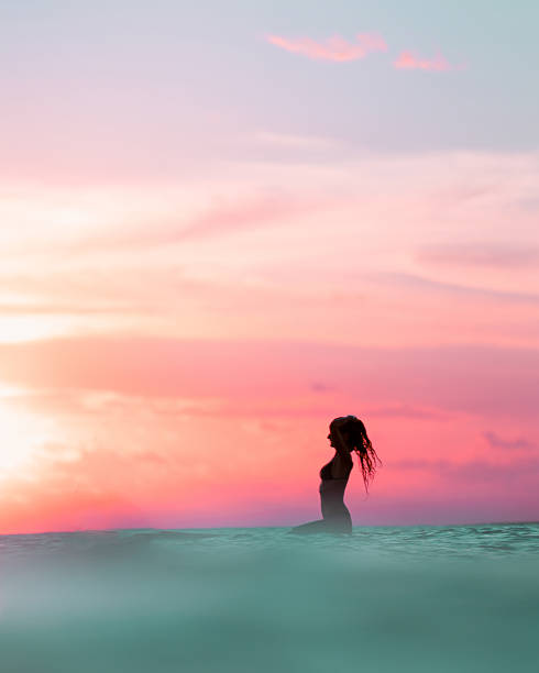 Gorgeous lady waiting for waves during a spectacular sunset in Rote, Indonesia