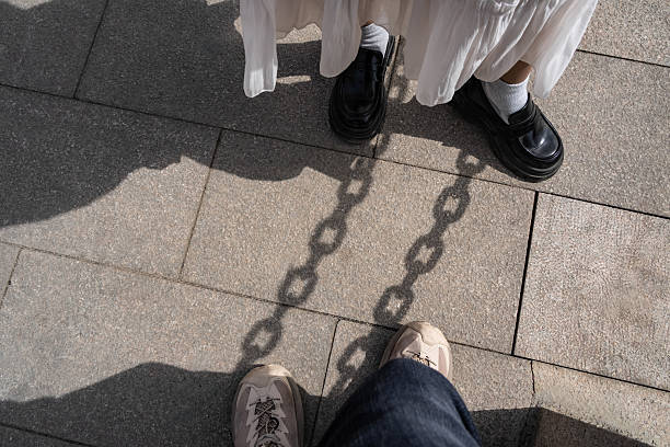 istock Couple legs stand on gray brick with chain shadow. 2222553764