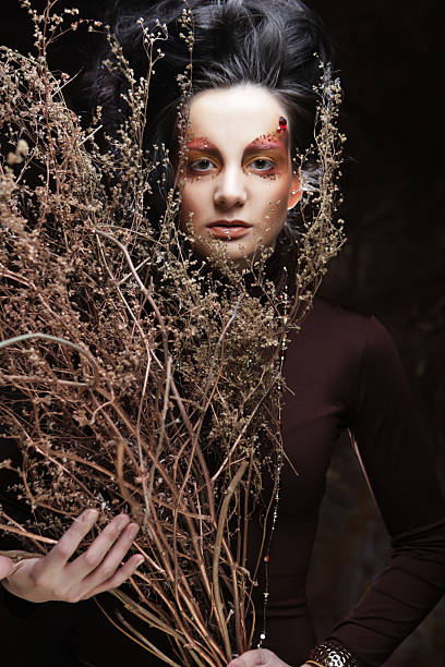 Young brunette woman with bright make up with dry branches