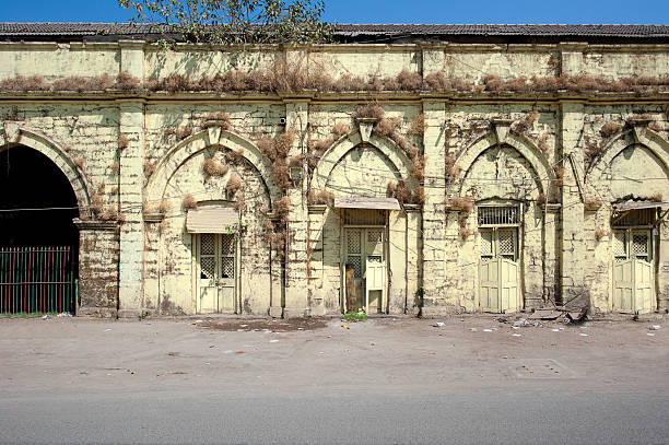 Wide angle of colonial warehouses, Junaghad Mullawada, Gujarat, India. Mullawada is a locality within the historic city of Junaghad, renowned for its architecturally significant sites, including temples, step wells and old imperial buildings but also for being one of the most contentious regions during the period of Partition in 1947. Gujarat, the north western state of India,  encompasses part of site of the Indus Valley civilisation, the oldest known to mankind and is also home to some of the most historic sites and religious locations in India. The Rann of Kutch is famous for its arid desert like landscapes as well as wildlife such as the Wild Ass, together with Gir Forest, home to the only Asiatic Lions in the continent.