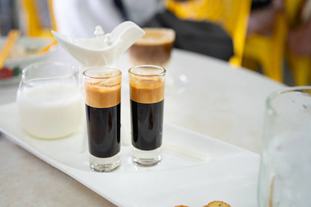 Vietnamese-style coffee served in clear glasses with thick crema on top, accompanied by a jug of milk on a white tray.