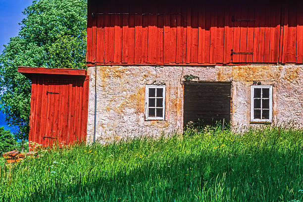Nynashamn, Stockholm County, Sweden - April 27, 2025: A red house with a white trim sits on a grassy lawn. The house has a large balcony and a flagpole in front of it. The house appears to be old and well-maintained