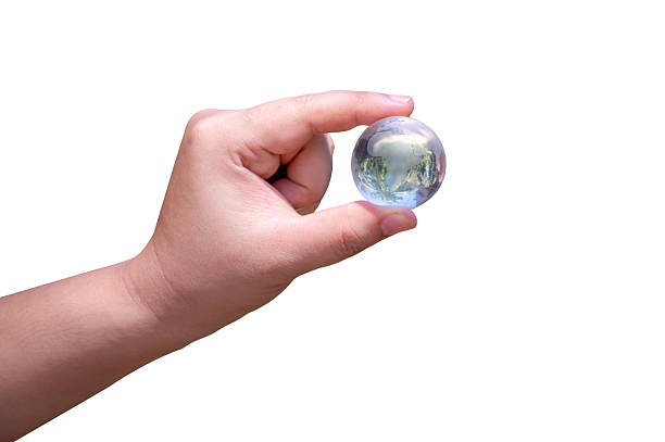 istock Female hand holding glass marble isolated on white background 2222572662