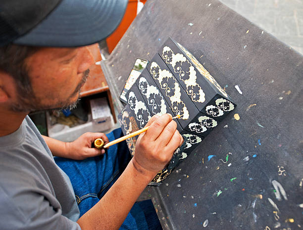 Artist at work, Norbulingka, Dharamshala, Himachal Pradesh, India. Norbulingka is dedicated to the preservation of Tibetan culture in all literary and artistic forms, based in Dharamsala, home to Tibetan refugees in exile and His Holiness the Dalai Lama. Himachal Pradesh, a state in the Western Himalayas of northern India, characterised by extreme landscapes of mountain peaks and extensive river systems.