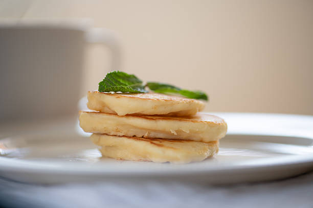 Pancakes of two sizes stacked on plates and placed on table