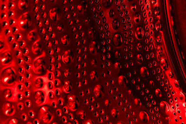 Empty washing machine drum inside in red light, close up view. Metal dots and bubbles as abstraction and background
