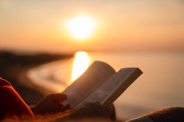 A man reading book against beautiful sunset on the beach. High quality photo