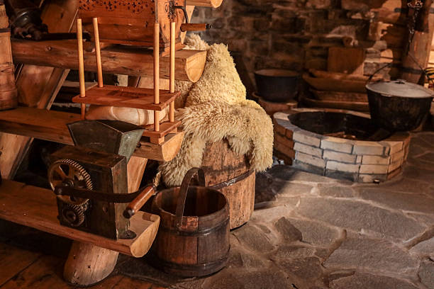 istock Rustic cottage workshop scene with antique hand-crank grain mill, wooden cheese press, sheepskin-covered barrel, bucket and stone hearth, celebrating traditional rural craftsmanship 2222581932