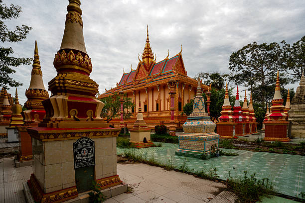 Bac Lieu, Vietnam – August 26, 2019: Decorative religious stupas of varying colors and sizes surround a large Buddhist temple in Bac Lieu. The ornate architecture, golden spires, and tiled grounds create a vivid spiritual landscape beneath a cloudy sky. The site reflects Southeast Asian cultural tradition.