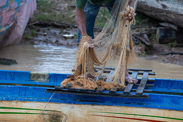 istock Fisherman pulling fishing net out of river from his boat 2222583010