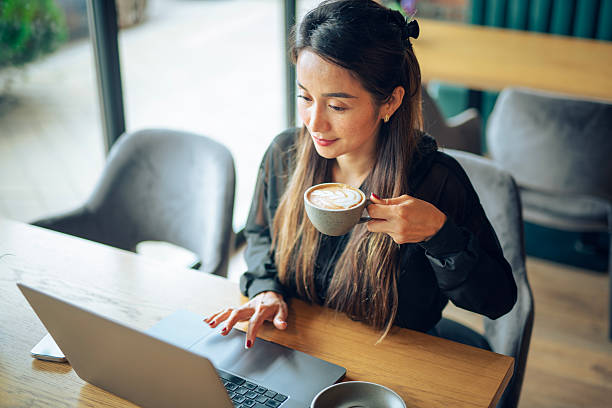 istock Asain woman having coffee while working on laptop at a cafe. 2222588493