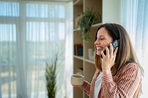 istock Young woman talking on phone and drinking coffee at home 2222596254